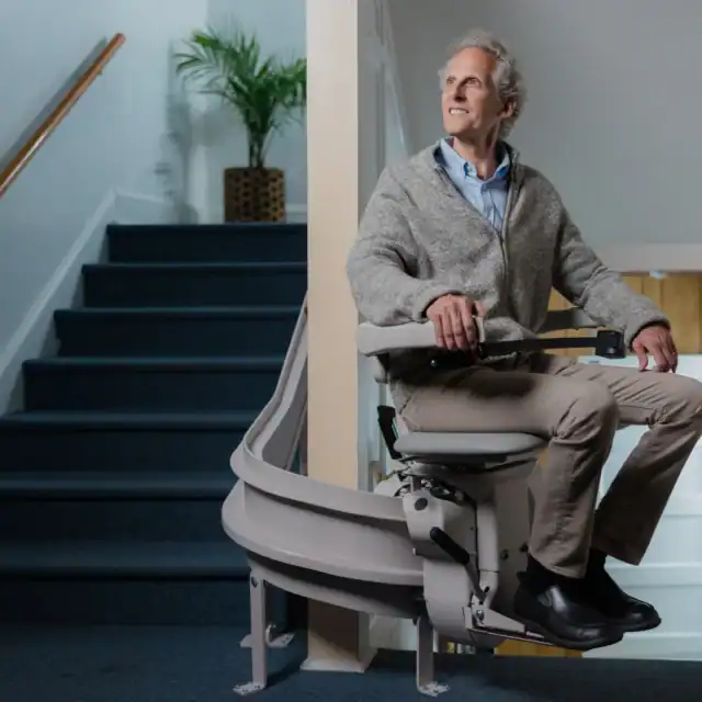 Older man rides a stairlift up stairs